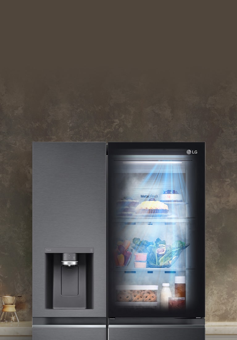 LG refrigerator with water dispenser on the left door and right door showcasing illuminated shelves of food.